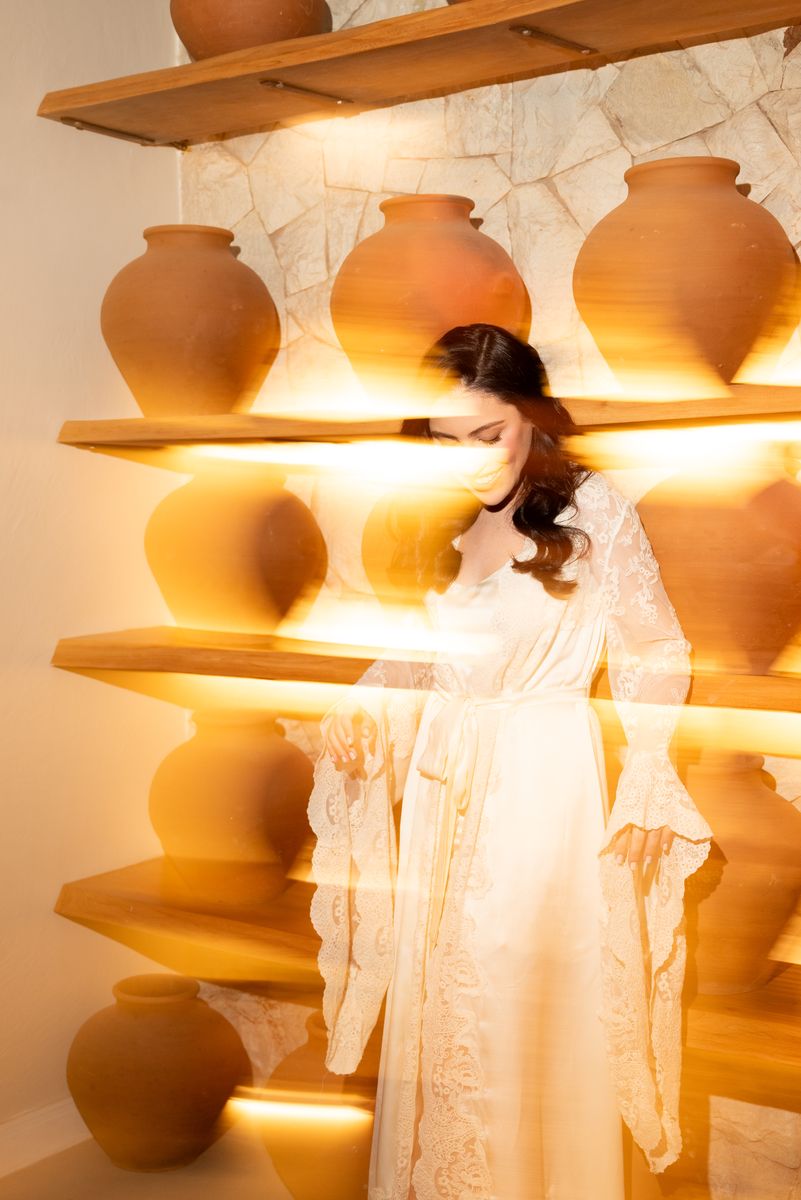 Noiva de robe entre vasos de cerâmica iluminados