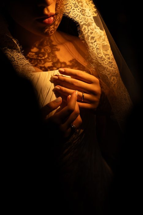 Mãos da noiva com a aliança, sob luz dourada