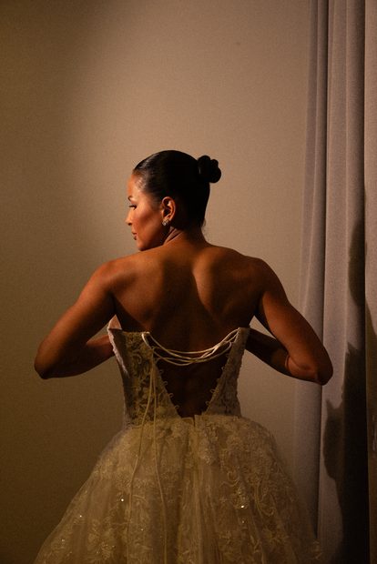 Noiva de costas com o vestido sendo fechado